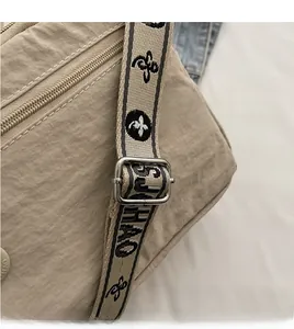 Detail of adjustable woven jacquard strap with floral patterns on a beige crossbody bag
