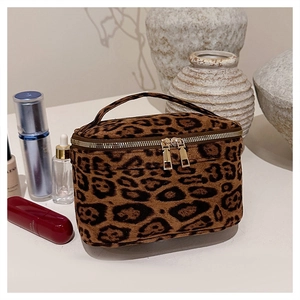 Détail d'une trousse à maquillage léopard avec double zip doré et poignée haute