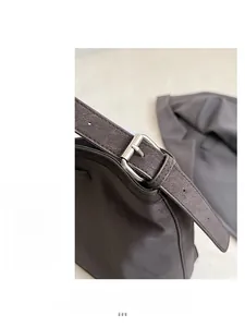 Close-up of high-quality silver metal buckle on a dark brown textured leather shoulder bag