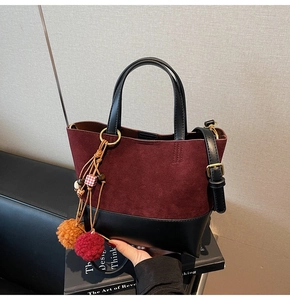 Detail of burgundy frosted and black leather拼接 hand bag with fuzzy bag charm accessory