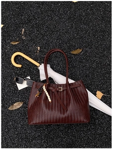Gros plan sur un cabas en cuir tressé marron foncé avec détails de sangles et accessoires