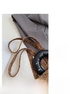 Detail of leopard print woven strap and black leather handle with silver metal rivets