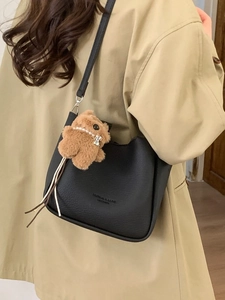 Black litchi grain leather bucket bag with a cute brown plush bear charm accessory