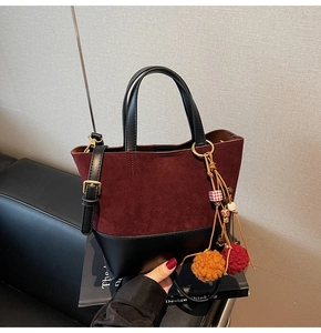 Detailed shot of two-tone burgundy suede and black leather bucket bag with tassel