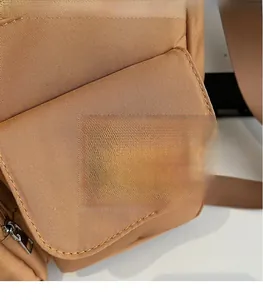 Detail of tan nylon tote bag showing embossed leather logo patch and fine stitching