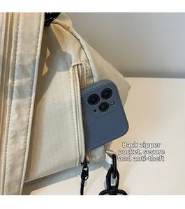 Close-up of beige plaid canvas backpack featuring an anti-theft hidden back zipper pocket