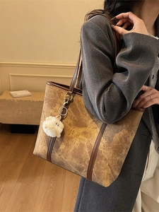 Minimalist marble pattern tote bag with brown leather trim and plush pom-pom accessory