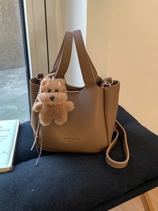 Brown litchi grain bucket bag with dual handles, crossbody strap and cute bear charm