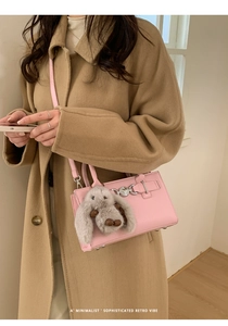 Detailed view of pink leather bag with silver metal ring buckle and plush rabbit charm