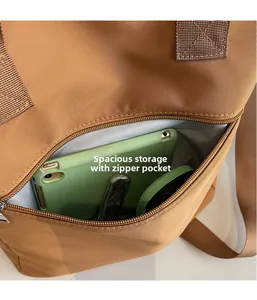 Macro view of brown nylon tote bag showing spacious main compartment and front zipper pocket