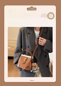Detail of brown suede bucket bag with white faux fur trim and gold metal buckle