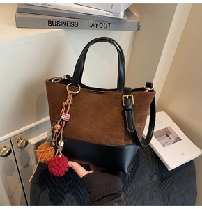 Detail of vintage bucket bag featuring brown suede stitching and colorful plush charm