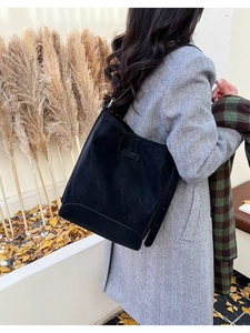 Detail of black suede large tote bag with curved bottom seam in an autumn park setting