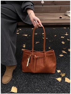Détail du sac cabas tressé marron vintage avec perles en bois sur sol en gravier noir