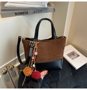 Detail of vintage brown suede tote bag with decorative tassel and adjustable strap