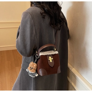 Detail of suede mini bucket bag with shearling trim, gold clasp and bear charm