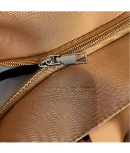 Macro shot of silver metal zipper puller on high-density brown woven fabric tote bag