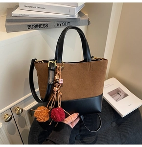 Detail of vintage tote bag with brown suede, black leather handles and fur ball charms