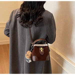Detail of suede bucket bag with cream faux fur trim and cute bear charm accessory