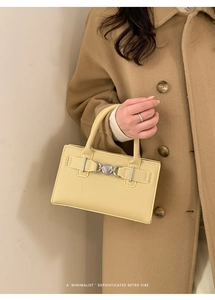 Close-up of minimalist retro yellow handbag with silver ring buckle and leather handle