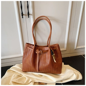 Détail du sac cabas marron tissé avec texture en V et breloque en perles colorées