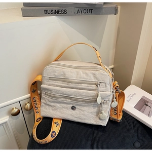 Detail of off-white multi-pocket crossbody bag with orange butterfly pattern strap