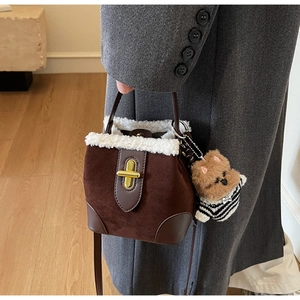 Detail of dark brown suede bucket bag with cream faux fur trim and cute dog charm