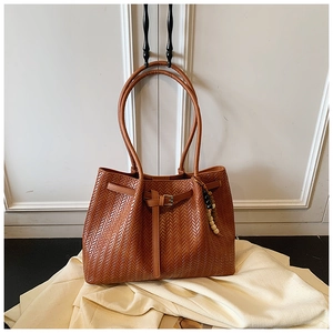 Détail de la texture tressée du sac cabas marron avec breloque ethnique et boucle en cuir