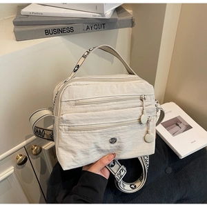 Close-up of beige multi-pocket crossbody bag with SJCHAO logo strap and triple zippers