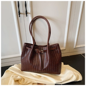 Gros plan du sac cabas tressé marron foncé montrant le motif en V et la boucle dorée