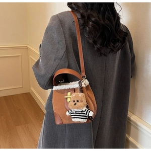 Detail of brown faux suede bucket bag with white fur trim and cute bear charm accessory
