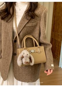Detail of khaki retro crossbody bag with heart buckle and gray bunny plush charm