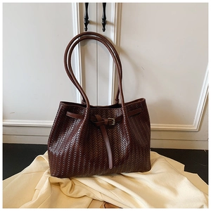 Vue détaillée d'un cabas tressé marron foncé avec boucle décorative et longues anses