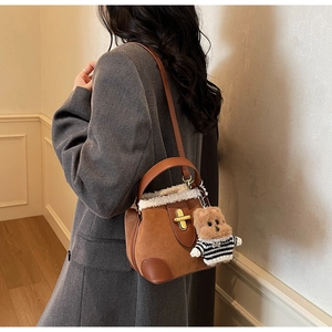 Brown suede bucket bag with shearling trim and cute teddy bear charm on model