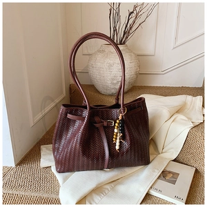 Détail du cabas tressé bordeaux avec texture huilée et pendentif en perles colorées