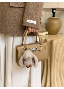 Detail of vintage beige leather handbag with metal lock and cute plush rabbit charm