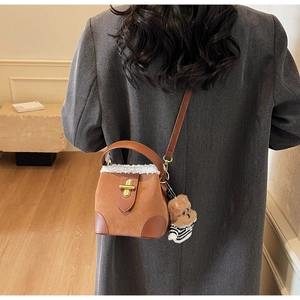 Close-up of brown suede crossbody bag with white fleece trim and cute bear charm