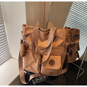 Detail of tan nylon tote bag showing multiple zipper pockets and mini round pouch
