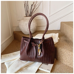Détail macro du sac cabas tressé marron foncé avec perles et lanière en cuir chic