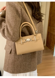 Detail of beige lychee textured handbag with silver heart lock and leather strap