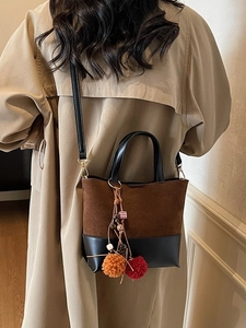 Vintage suede leather patchwork tote bag with tassel charm shown on beige trench coat