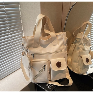 Detail view of large cream tote bag with multiple pockets and detachable coin purse