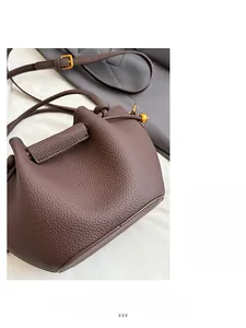 Detailed close-up of dark brown lychee leather bucket bag with gold spherical hardware