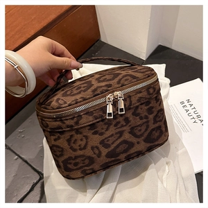Détail de la trousse de maquillage léopard avec poignée et double fermeture éclair dorée