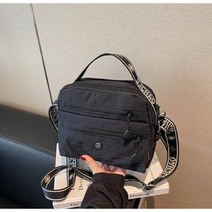 Detail of waterproof black nylon crossbody bag with multi-zipper pockets and wide strap