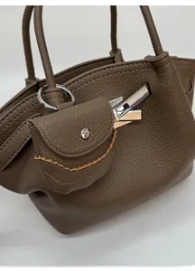 Detail of coffee brown pebble leather texture and silver metal clasp on bucket bag