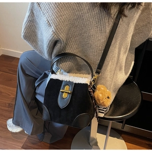 Close-up of suede crossbody bag with white faux fur trim and cute bear keychain