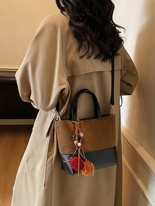 Vintage color-block crossbody bucket bag with pom-pom charm on a khaki trench coat model