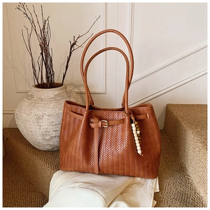 Détail du sac cabas marron tissé avec texture cuir et pompon décoratif en perles