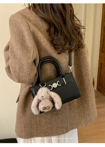 Detail of retro black pebble leather crossbody bag with silver hardware and rabbit charm